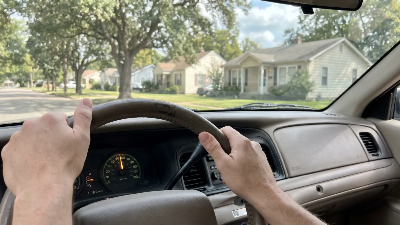 The interior of an ordinary American left-hand-drive car dashboard in daylight with a plain analog radio dial lit