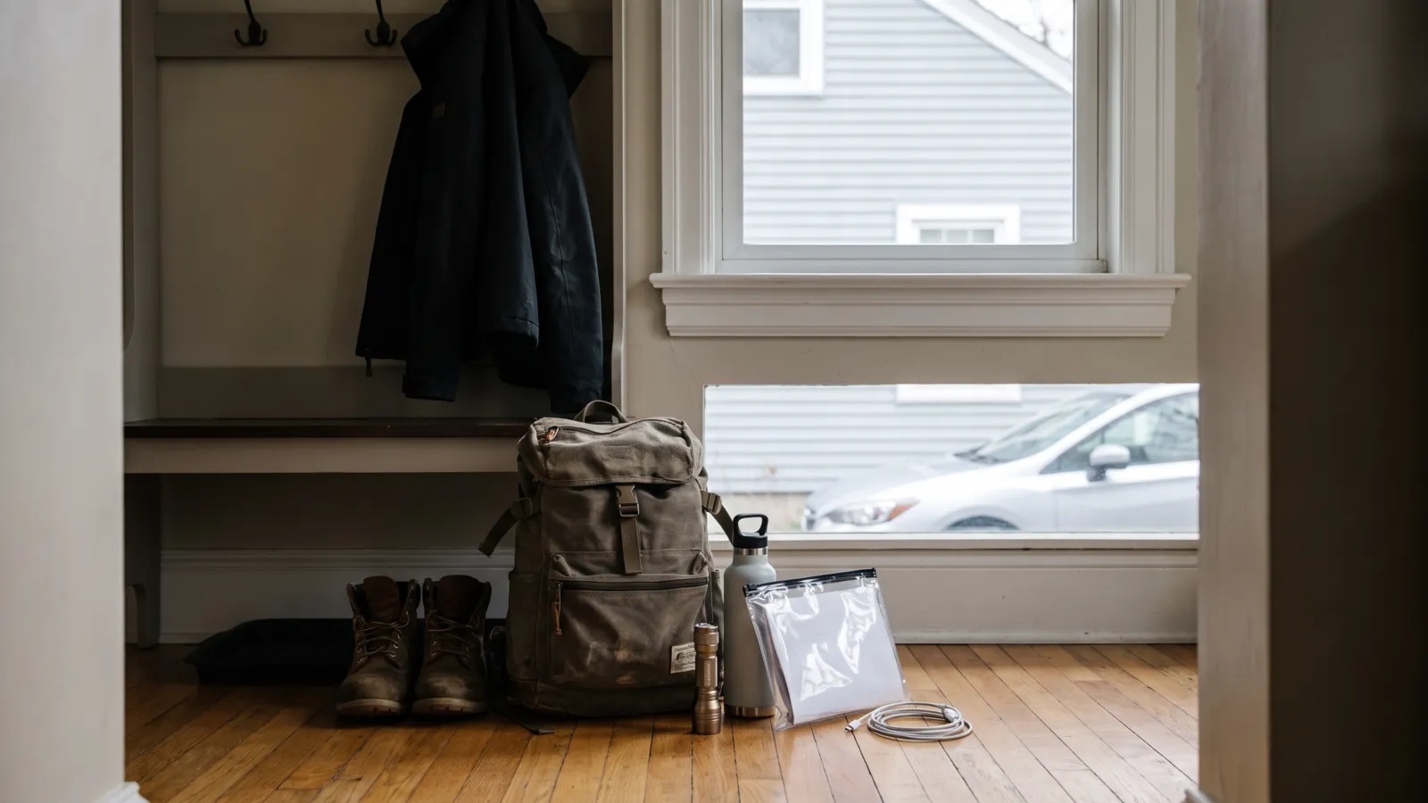 A packed backpack go-bag on the floor by the front door of an American house